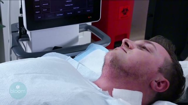 A patient resting on the treatment table beside the ultrasound cart